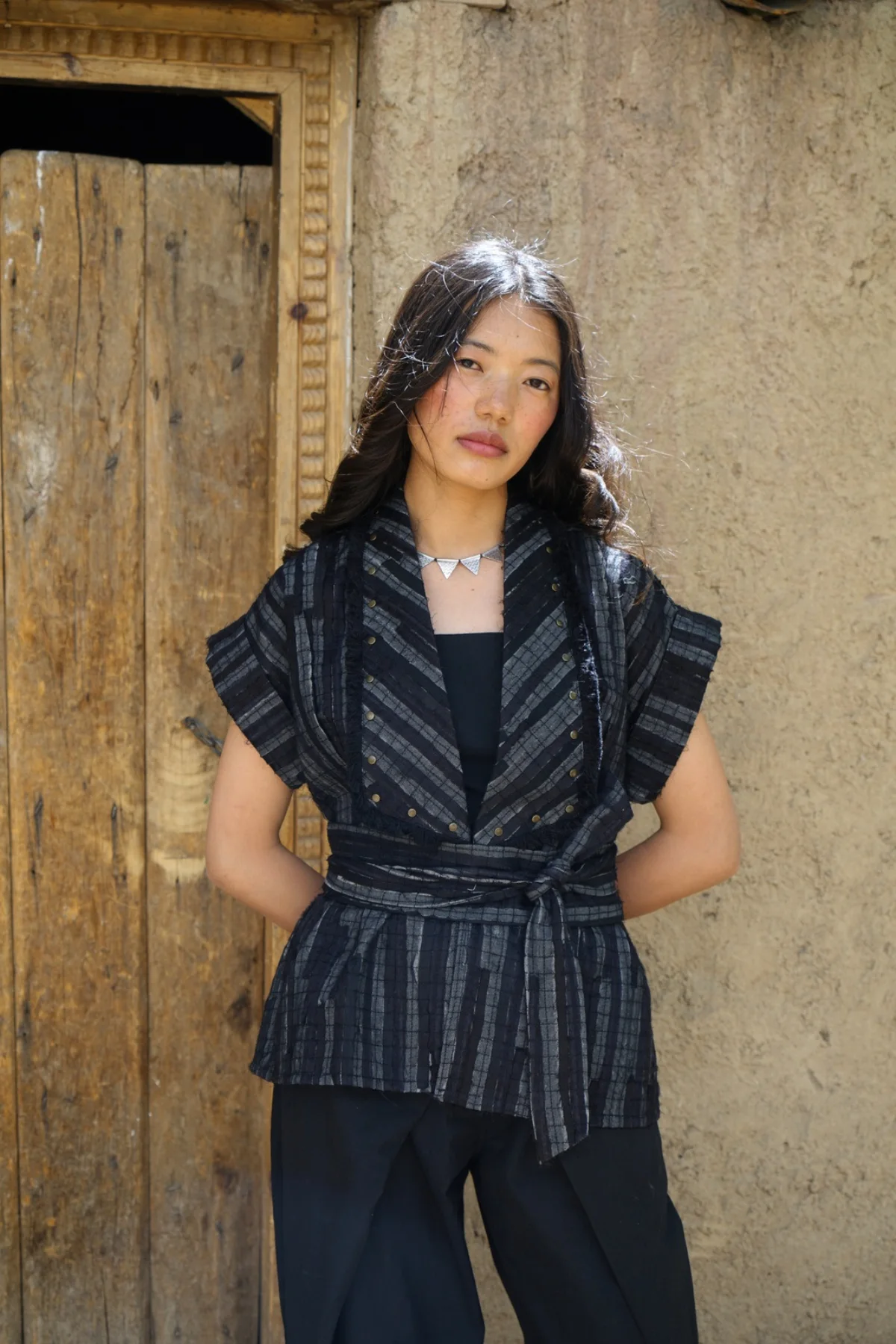Model wearing a structured black wrap top with wide trousers