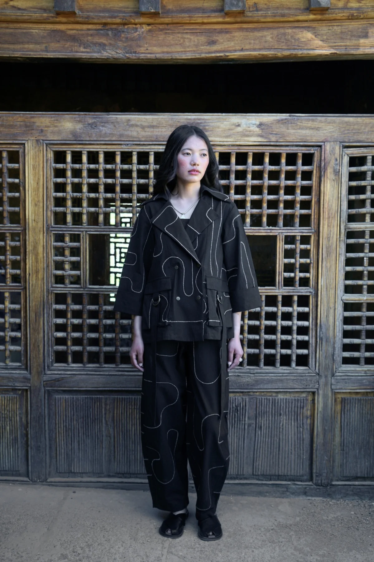 Model wearing a black graphic jacket and matching trousers