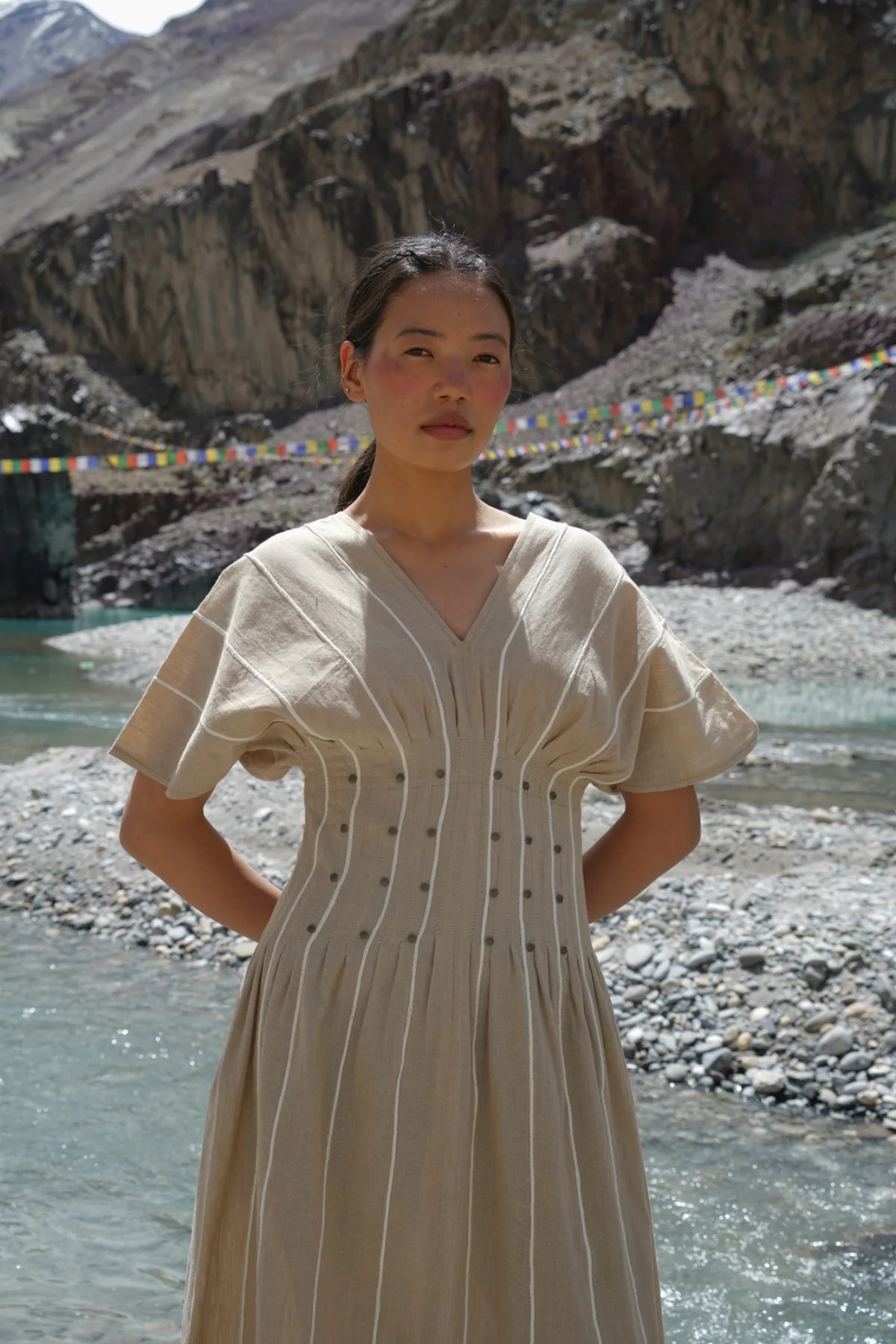 Model wearing a light neutral dress in a mountain landscape