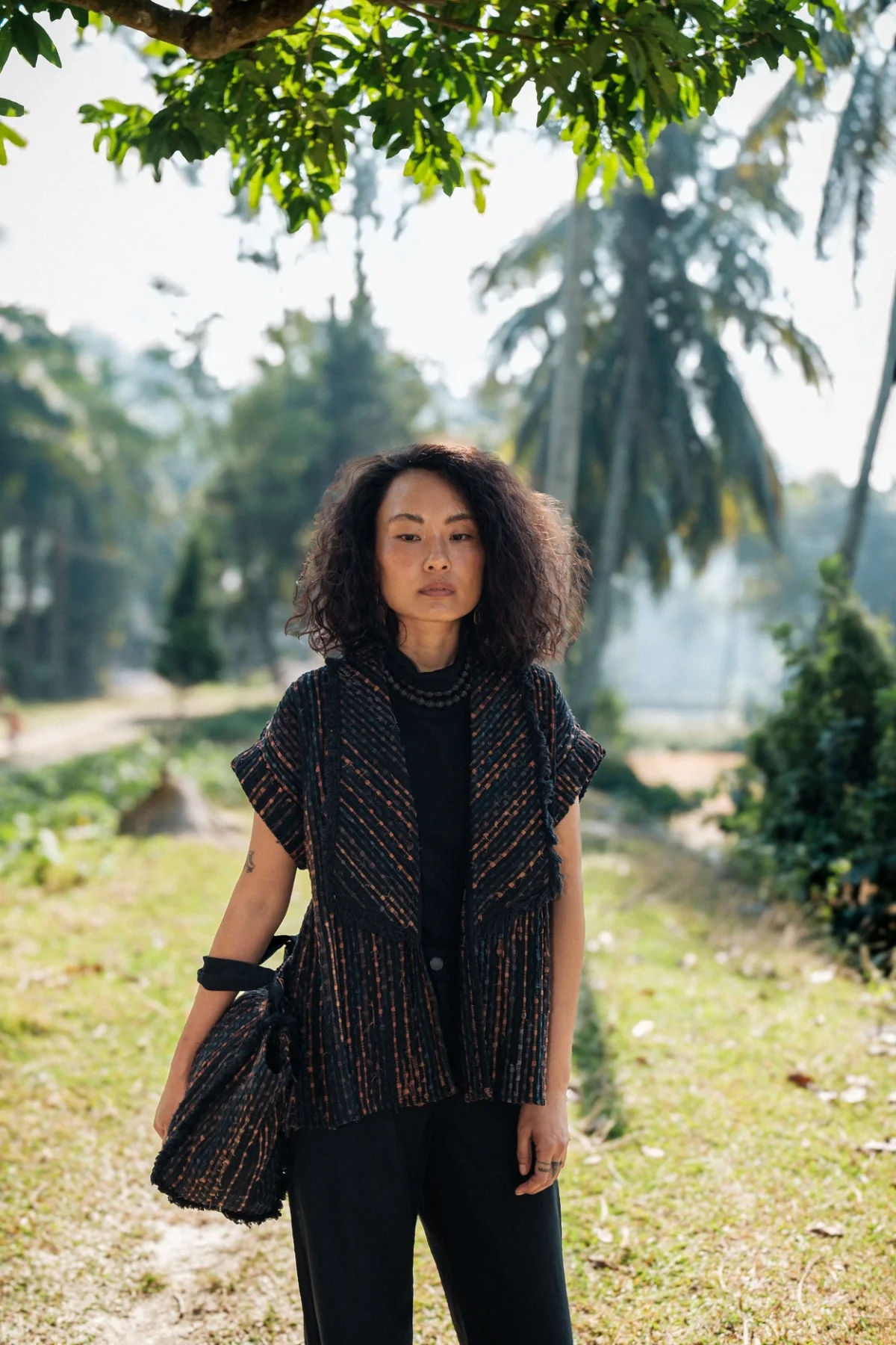Model wearing a dark patterned sleeveless top outdoors