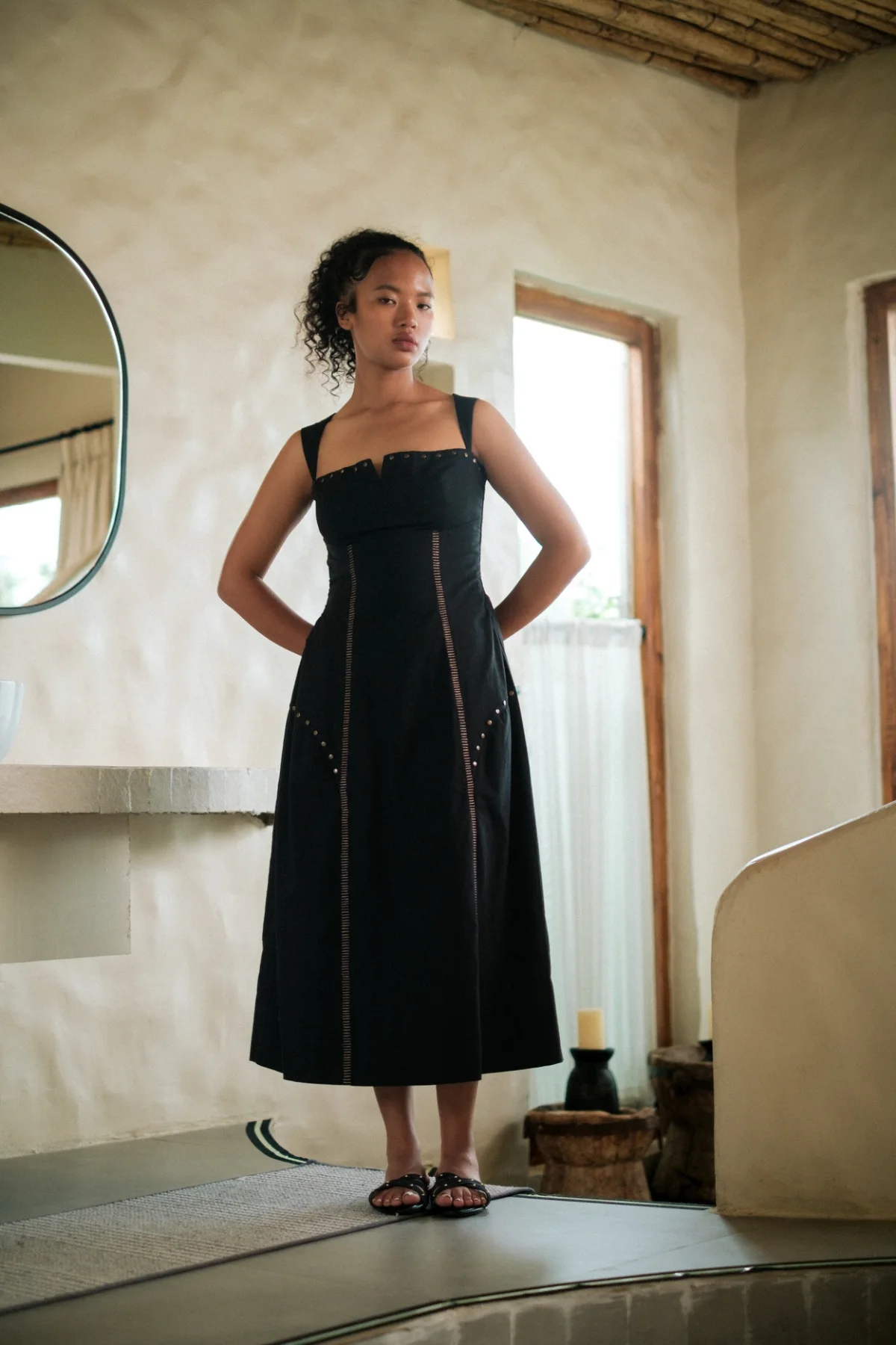 Model wearing a long black dress in a warm neutral interior